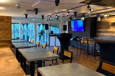 Miniature Location salle Braine-l'Alleud (Brabant wallon) - Le Moulin Blanc #17 Salle lumineuse avec parquet clair, table et chaises au centre, escalier blanc, machine à coudre ancienne et tableau au mur.