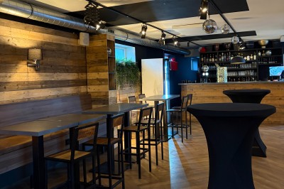 Miniature Location salle Braine-l'Alleud (Brabant wallon) - Le Moulin Blanc #16 Salle lumineuse avec parquet clair, table et chaises au centre, escalier blanc, machine à coudre ancienne et tableau au mur.