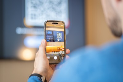 Une main verse un cocktail rose dans un verre décoré d'une tranche de citron vert, avec des boissons et snacks en arrière…