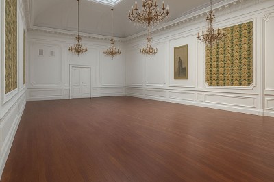 Salle de réunion lumineuse avec de longues tables blanches, chaises noires, écran mural et tableau blanc.