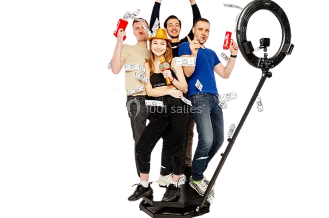 Quatre personnes posent joyeusement sur une plateforme avec des accessoires festifs et des billets en papier autour d'eux.