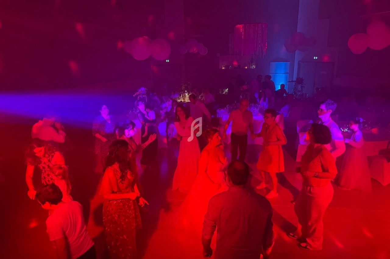 Personnes dansant dans une salle éclairée par des lumières rouges et bleues, ambiance festive en soirée.