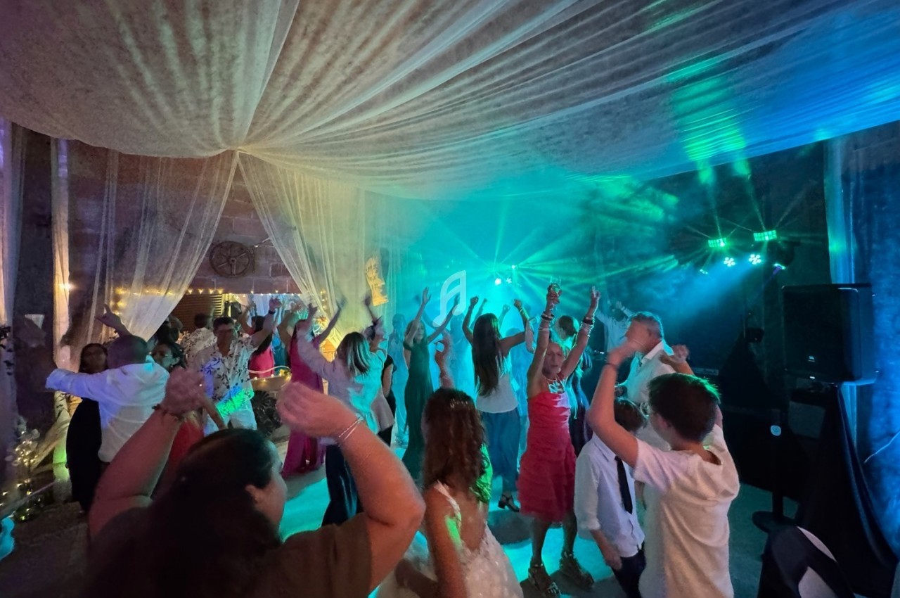 Des personnes dansent sous un éclairage coloré dans une salle décorée avec des voilages suspendus.