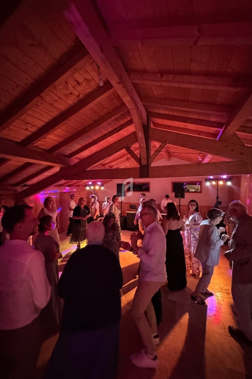 Personnes dansant dans une salle en bois avec éclairage coloré et ambiance festive.