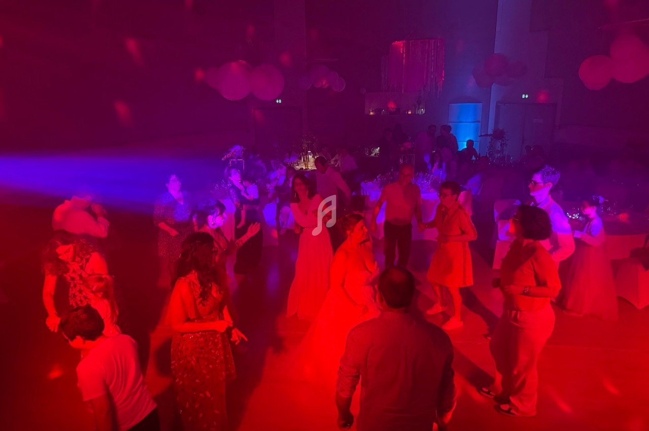Personnes dansant dans une salle éclairée par des lumières rouges et bleues, ambiance festive en soirée.