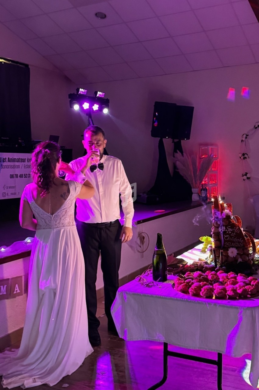 Un couple en tenue de mariage partage un moment devant une table garnie de desserts et de décorations festives.
