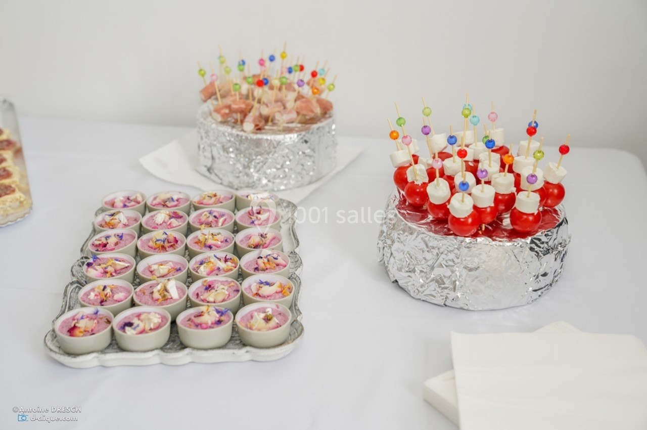 Plateau de verrines colorées et brochettes apéritives disposés sur une table blanche pour un buffet.