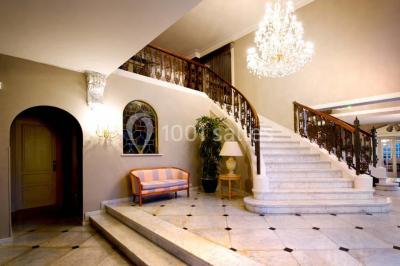 Lustre en cristal allumé suspendu au-dessus d'un escalier avec rampe en fer forgé et sol en marbre.