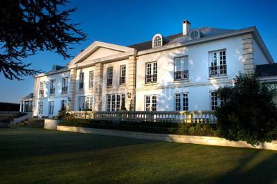 Lustre en cristal allumé suspendu au-dessus d'un escalier avec rampe en fer forgé et sol en marbre.