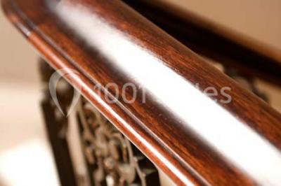 Lustre en cristal allumé suspendu au-dessus d'un escalier avec rampe en fer forgé et sol en marbre.