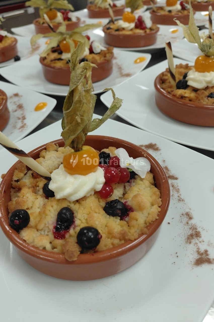 Desserts individuels en ramequins garnis de crumble, fruits rouges, physalis, chantilly et décor en chocolat.