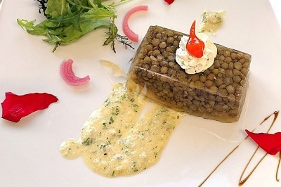 Filet de poisson avec sauce au vin rouge, purée, lard croustillant et garniture de champignons sur une assiette blanche.
