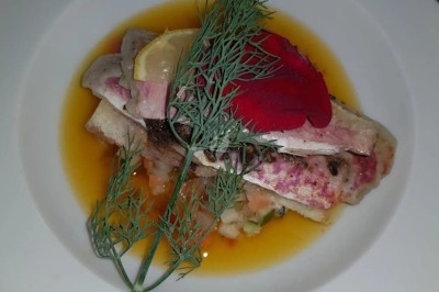 Filet de poisson nappé de sauce brune, accompagné de purée, lard croustillant et garniture de champignons.