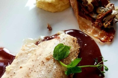 Filet de poisson nappé de sauce brune, accompagné de purée, lard croustillant et garniture de champignons.