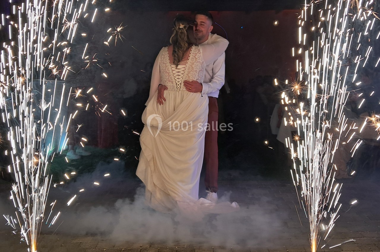 Un couple danse entouré de fontaines d'étincelles et de fumée lors d'une célébration en soirée.