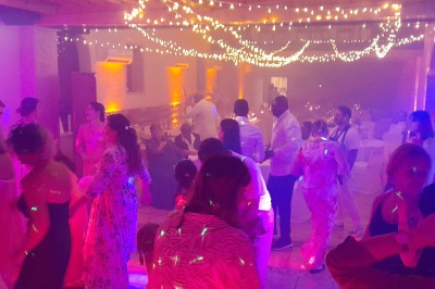 Miniature DJ Heyrieux (Isère) - Ld Animations #15 Un couple en tenue de mariage danse dans une salle éclairée par des lumières colorées et entourée de fumée.