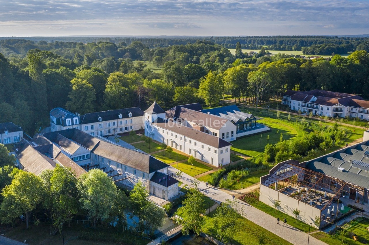 Vue aérienne d'un domaine avec bâtiments anciens rénovés, entouré de verdure et de paysages champêtres.