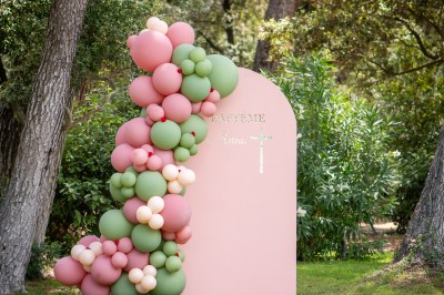 Centre de table floral coloré avec des roses et des verres disposés sur une nappe blanche, bougie en arrière-plan.