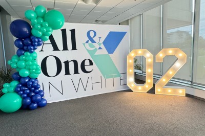 Centre de table floral coloré avec des roses et des verres disposés sur une nappe blanche, bougie en arrière-plan.