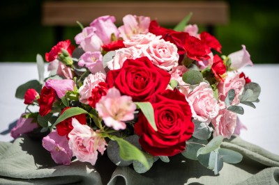 Salle de réception décorée pour un mariage, avec tables dressées, chandeliers suspendus et poutres apparentes au plafond.