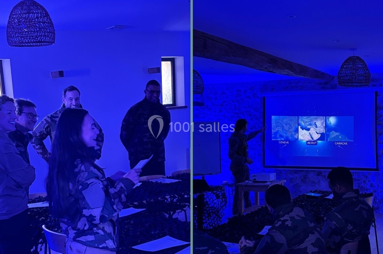 Des personnes en tenue militaire assistent à une présentation dans une salle éclairée par une lumière bleue.