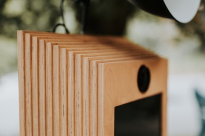 Appareil photo sur trépied en bois avec lampe circulaire, installé dans un jardin verdoyant.