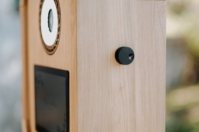 Miniature Lively Booth #5 Appareil photo en bois monté sur un trépied, installé dans un jardin avec des arbres en arrière-plan.