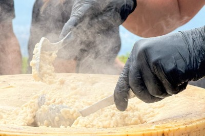 Miniature Traiteur Saint-Vallier-de-Thiey (Alpes-Maritimes) - Traiteur D'azur #10 Un cuisinier en tenue noire prépare des légumes dans une poêle en extérieur, devant un mur en pierre.
