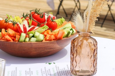 Miniature Traiteur Saint-Vallier-de-Thiey (Alpes-Maritimes) - Traiteur D'azur #11 Un cuisinier en tenue noire prépare des légumes dans une poêle en extérieur, devant un mur en pierre.