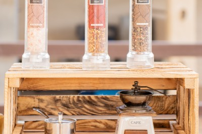 Miniature Traiteur Saint-Vallier-de-Thiey (Alpes-Maritimes) - Traiteur D'azur #12 Un cuisinier en tenue noire prépare des légumes dans une poêle en extérieur, devant un mur en pierre.