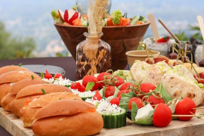 Miniature Traiteur Saint-Vallier-de-Thiey (Alpes-Maritimes) - Traiteur D'azur #3 Un cuisinier en tenue noire prépare des légumes dans une poêle en extérieur, devant un mur en pierre.