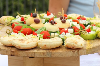 Miniature Traiteur Saint-Vallier-de-Thiey (Alpes-Maritimes) - Traiteur D'azur #4 Un cuisinier en tenue noire prépare des légumes dans une poêle en extérieur, devant un mur en pierre.