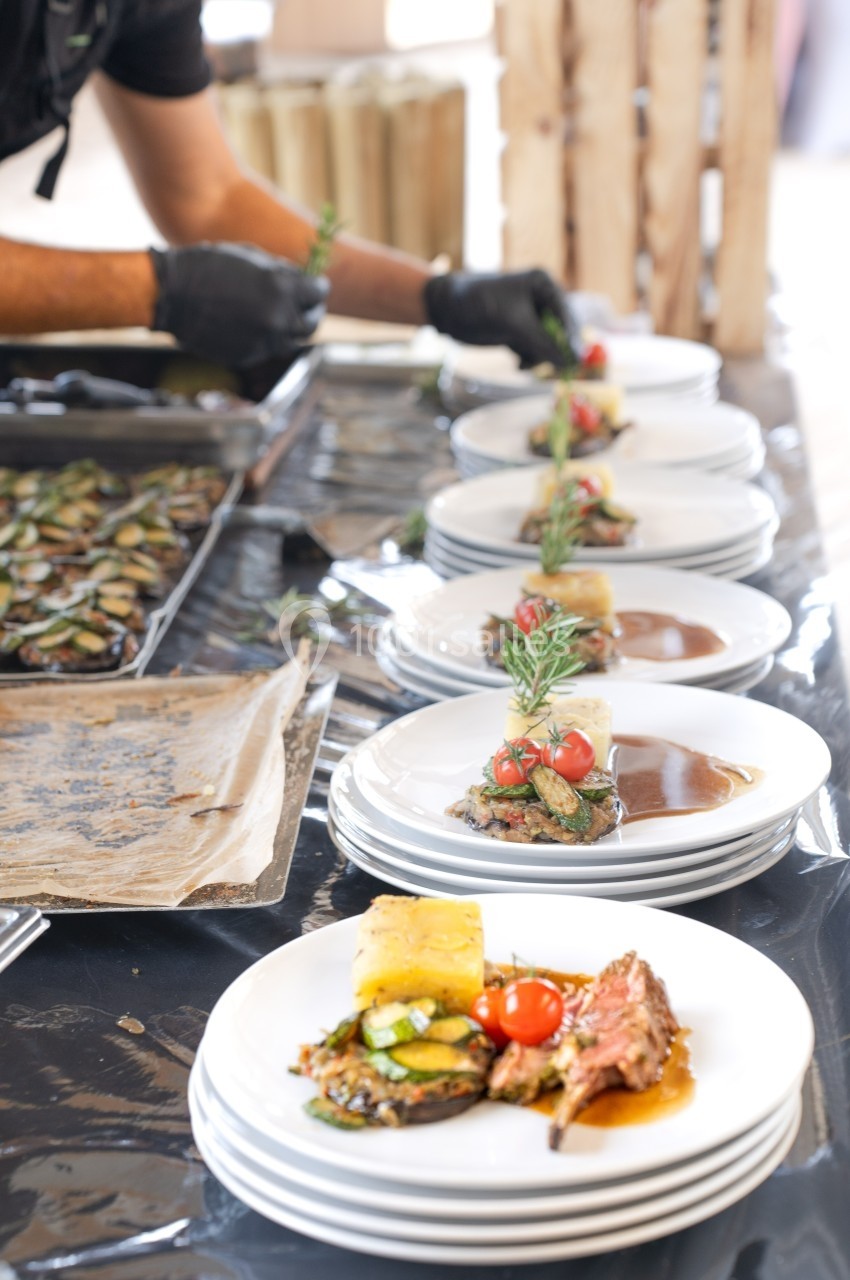 Assiette de viande grillée avec légumes, sauce et décoration de romarin, préparée sur une table de service.