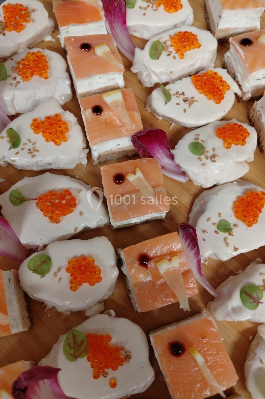 Plateau de bouchées apéritives avec saumon fumé, crème, œufs de poisson et décorations florales.