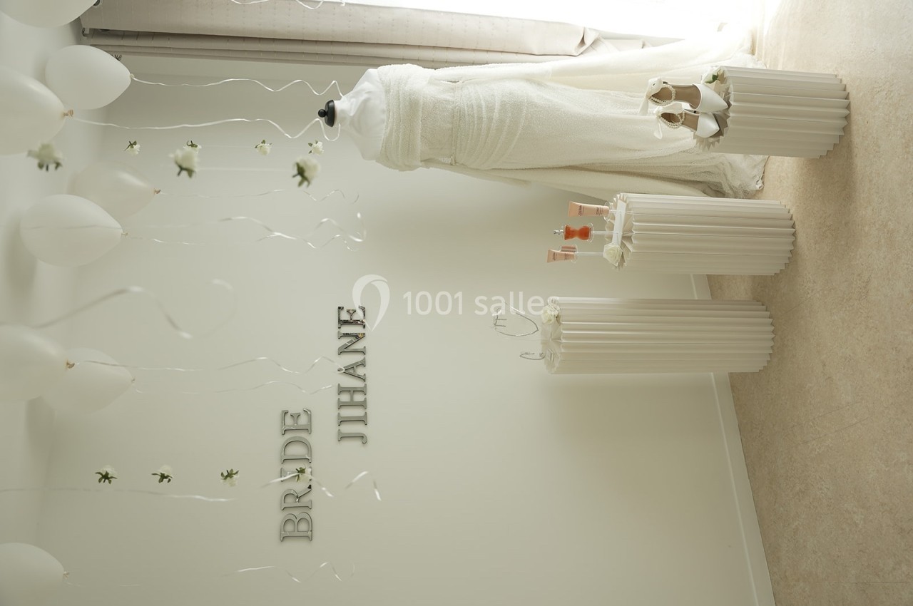 Mannequin habillé d'une robe de mariée blanche, entouré de ballons et de décorations minimalistes dans une pièce lumineuse.