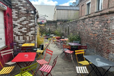 Miniature Location salle Lille (Nord) - Le W #4 Terrasse extérieure avec tables et chaises colorées, entourée de murs en briques et végétation.