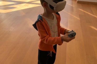 Homme portant un casque de réalité virtuelle et tenant deux manettes dans une pièce au sol en bois.