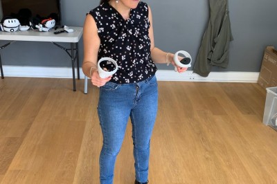 Homme portant un casque de réalité virtuelle et tenant deux manettes dans une pièce au sol en bois.