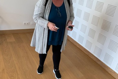 Homme portant un casque de réalité virtuelle et tenant deux manettes dans une pièce au sol en bois.