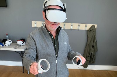 Un homme utilise un casque de réalité virtuelle avec des manettes dans une pièce équipée de crochets muraux.