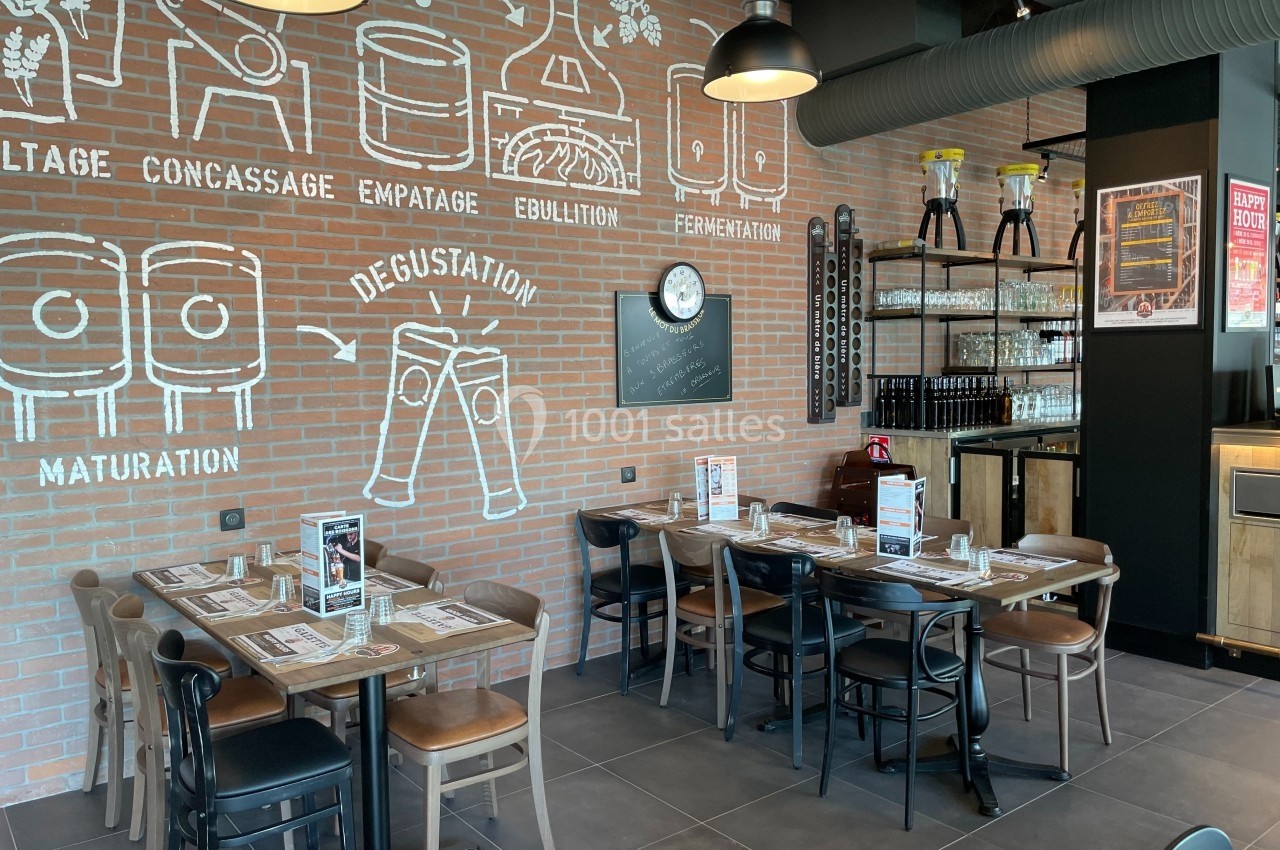 Salle de restaurant avec tables dressées, décor mural sur le processus de fabrication de la bière et étagères en arrière…