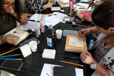 Miniature Mk Team Building #7 Des personnes tiennent un parachute coloré avec des trous, utilisé pour une activité de groupe en extérieur sur une pelouse.