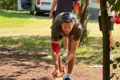 Miniature Mk Team Building #8 Des personnes tiennent un parachute coloré avec des trous, utilisé pour une activité de groupe en extérieur sur une pelouse.