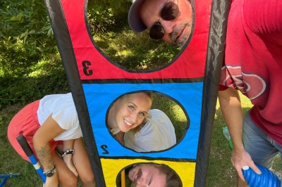 Miniature Mk Team Building #9 Des personnes tiennent un parachute coloré avec des trous, utilisé pour une activité de groupe en extérieur sur une pelouse.