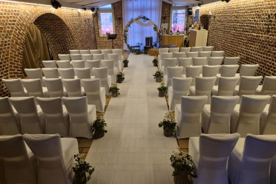 Espace extérieur aménagé pour un événement avec tables hautes, buffet et tente blanche, entouré de verdure.