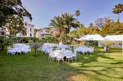 Deux fauteuils en rotin et une table basse avec une tasse, sur une terrasse donnant sur un jardin verdoyant.