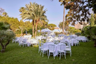 Deux fauteuils en rotin et une table basse avec une tasse, sur une terrasse donnant sur un jardin verdoyant.