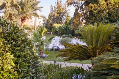 Deux fauteuils en rotin et une table basse avec une tasse, sur une terrasse donnant sur un jardin verdoyant.