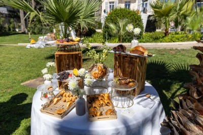 Deux fauteuils en rotin et une table basse avec une tasse, sur une terrasse donnant sur un jardin verdoyant.