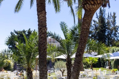 Deux fauteuils en rotin et une table basse avec une tasse, sur une terrasse donnant sur un jardin verdoyant.